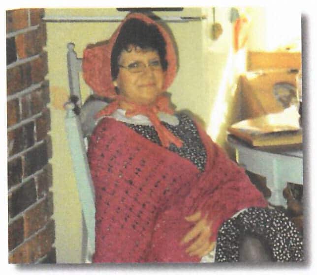 Grandmother Betty Stewart (Yaya) sits in her chair sporting a red cover and bonnet