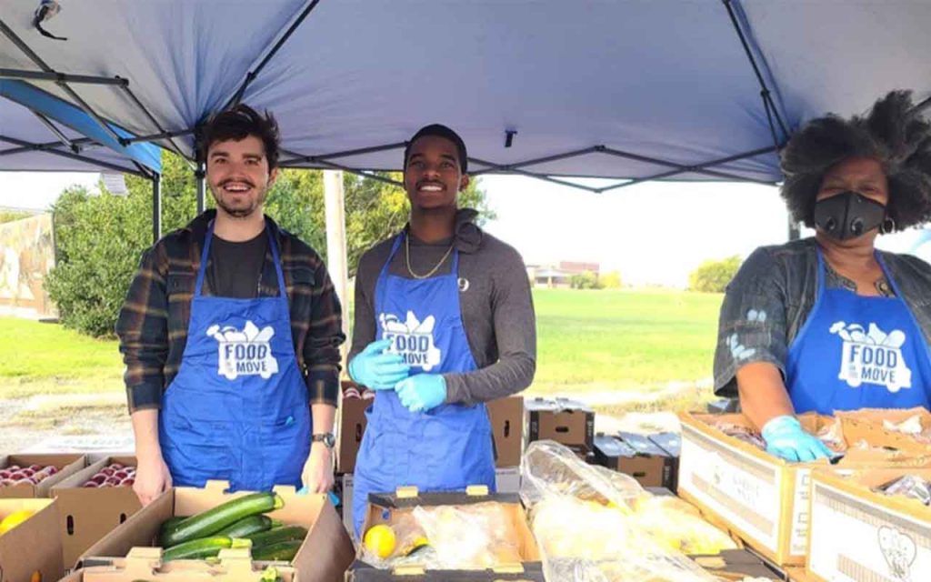 Smiling volunteers behind a table of food