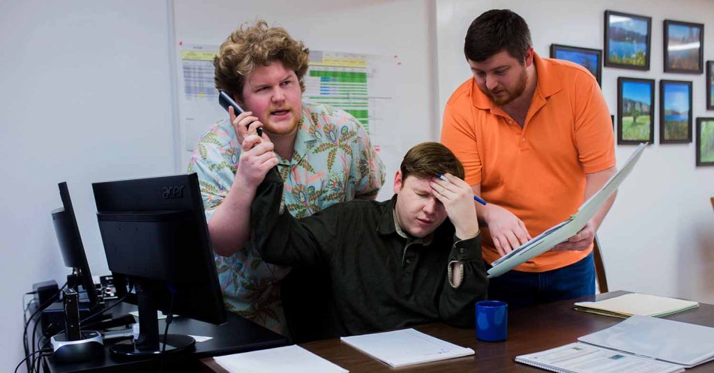 men at an office desk doing work