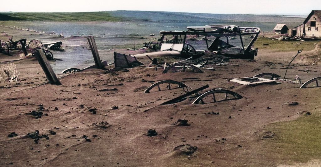 Image of a old car nearly completely buried in dirt. - colorized